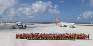Eine Gruppe von Menschen post vor zwei zivilen Flugzeugen aus dem Fiery Cross Atoll
