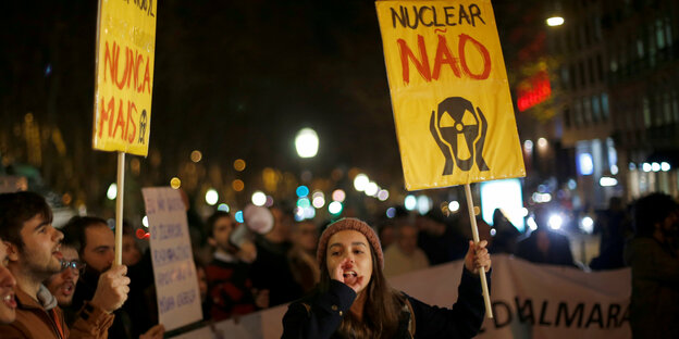 Menschen halten Schilder gegen Atomkraft in den Händen und rufen