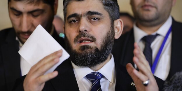 Mohammed Alloush mit einem Zettel in der rechten, erhobenen Hand