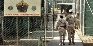 Zwei Wärter laufen durch einen schwer geseicherten Eingang zu Guantanamo
