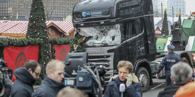 Der Lkw, mit dem der Anschlag von Breitscheidplatz verübt wurde steht mit zersplitterter Frontscheibe auf dem Weihnachtsmarkt, drum herum telefonieren hektisch Polizisten