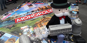 Ein Monopolymännchen sitzt auf einem großen Monopolybrett