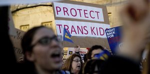 Demonstrantinnen halten ein Schild hoch: "protect trans kid" steht darauf