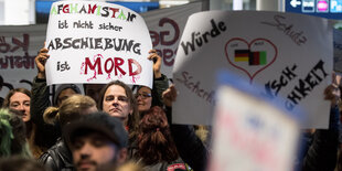 Menschen mit Transparenten und Plakaten stehen in einem Gebäude