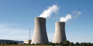 Zwei dampfende Schlote eines Kernkraftwerks vor blauem Himmel