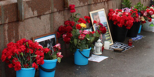 Plastikeimer mit Blumen und Fotos auf einer Brücke in Moskau