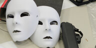 zwei weiße Theatermasken liegen auf einem Aktenordner