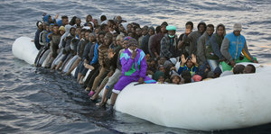 viele schwarze Menschen sitzen in einem überfüllten Schlauchboot