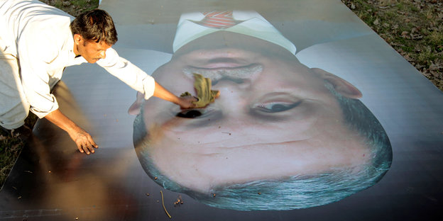 Ein Mann putzt ein Plakat, auf dem der türkische Staatschef Erdogan abgebildet ist
