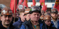 Männer mit Helmen schauen besorgt bei einer Demo