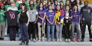 Kanzlerin Merkel steht mit Fußballspielerinnen, eine hat eine tibetische Flagge umgehängt