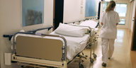 Eine Krankenschwester läuft in einem Flur an einem Krankenbett vorbei