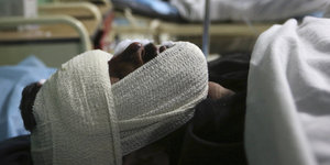 Ein Mann mit Verband um seinen Kopf liegt in einem Krankenhausbett