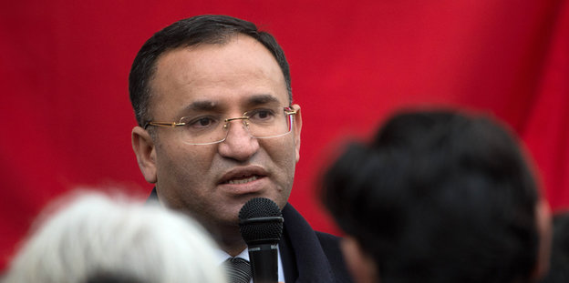 Der türkische Justizminister Bekir Bozdag mit Mikro vor rotem Hintergrund