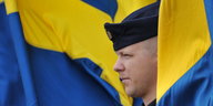 Porträt eines Soldaten zwischen schwedischen Flaggen