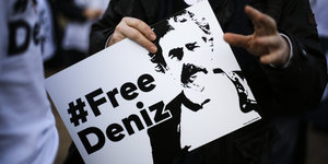 Ein Mensch hält ein Schild, auf dem „#Free Deniz“ steht