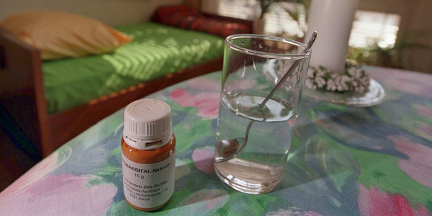 Ein Medikament und ein Glas Wasser auf dem Tisch