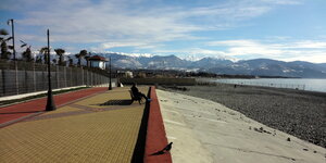 Eine Strandpromenade, im Hintergrund schneebedeckte Berge