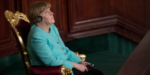 Merkel auf einem Stuhl mit Goldverziehrung