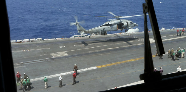 Von einer Landebahn hebt ein Helikopter ab. Sie befindet sich auf einer Plattform im Meer
