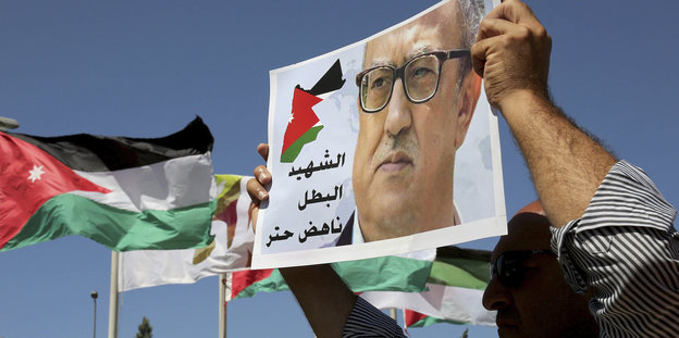 Demonstranten halten die jordanische Flagge und ein Banner mit dem Gesicht des ermordeten Nahed Hattar in die Höhe