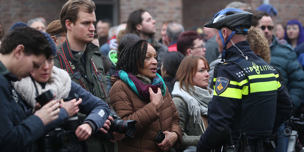 Schaulustige und Journalisten in den Niederlanden stehen einem Polizisten gegenüber
