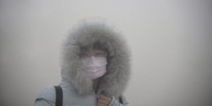 Eine Fraum mit Atemmaske im Smog
