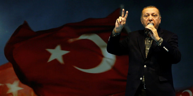 Erdogan steht vor einer türkischen Flagge