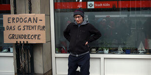 Eine demonstrierende Person mit einem Plakat, auf dem „Erdogan - und das G steht für Grunrechte“ steht