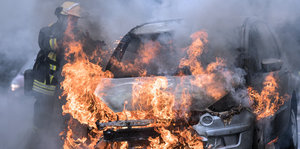 Brennendes Fahrzeug - ein Feuerwehrmann ist am Löschen