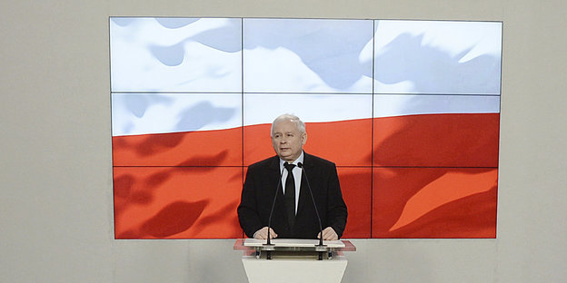 Kaczynski an einem Rednerpult vor polnische Flagge