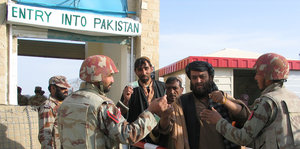 Männer laufen durch ein Tor mit der Aufschrift "Entry into Pakistan"