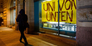 Passantin läuft an Schaufenster mit Banner "Uni von unten" vorbei