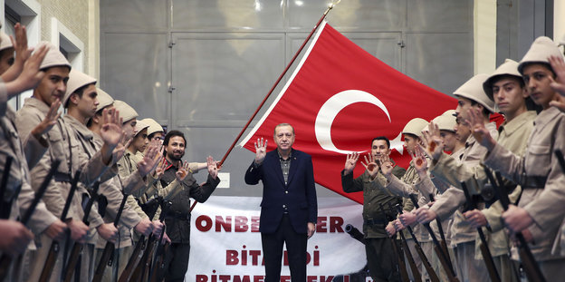 Erdogan zeigt zwischen Spalier stehendenjugendlichen Unterstützern den Rabia-Gruß