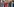Eine junge rothaarige Frau betrachtet eine pinkfarbene Jacke, die unter vielen anderen Kleidungsstücken auf einer Stange hängt