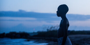 Ein Junge steht im Abendrot am Strand