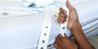 Eine Krankenschwester fixiert den Gurt an einem Krankenbett