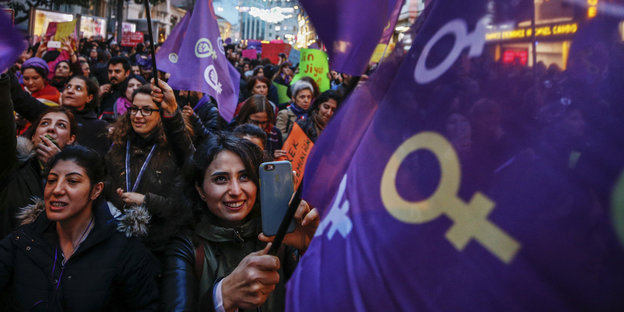 Lachende Frauen mit lialafarbenen Fahnen ziehen zum Frauentag durch Istanbul