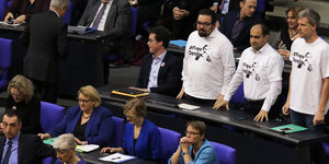 Drei Grüne Bundestagsabgeordnete in weißen T-Shirts mit der Aufschrift #FreeDeniz stehen zwischen den Sitzenden im Bundestag