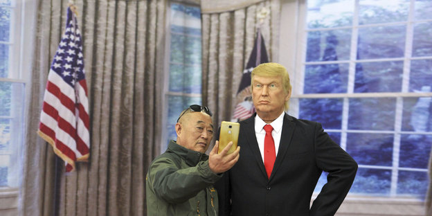 Ein Mann macht ein Selfie, neben ihm eine Trump-Figur aus Wachs