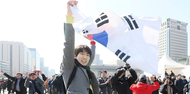 Junger Mann winkt mit Südkoreas Flagge