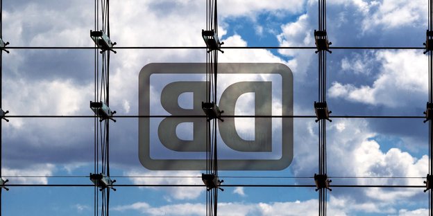 Spiegelverkehrtes Bahnlogo an Glasfassade vor leicht bedecktem Himmel