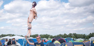 Ein junger Mann hält eine aufgelasene Sexpuppe auf einem Festival in die Luft
