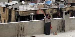 Eine Frau guckt auf zerstörte Häuser
