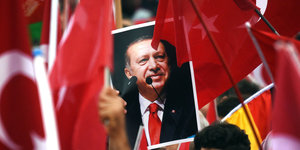 Türkische Fahnen, dazwischen ein Porträtbild Erdogans