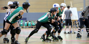 Sportlerinnen der Riot Rocketz fahren in einer Turnhalle mit Rollschuhen