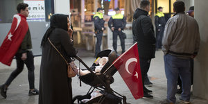 Frau mit Kinderwagen, an dem eine türkische Fahne befestigt ist