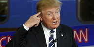 Donald Trump hält eine Rede und hält sich den Zeigefinger an die Schläfe