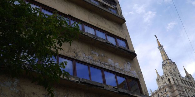 Eine zerfallende Gebäudefassade im Vordergrund und ein glänzender Stalin-Bau im Hintergrund