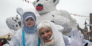 eine Mutter und ihr Kind im Eisbärkostüm vor einem riesigen Eisbären auf einem Karnevalswagen
